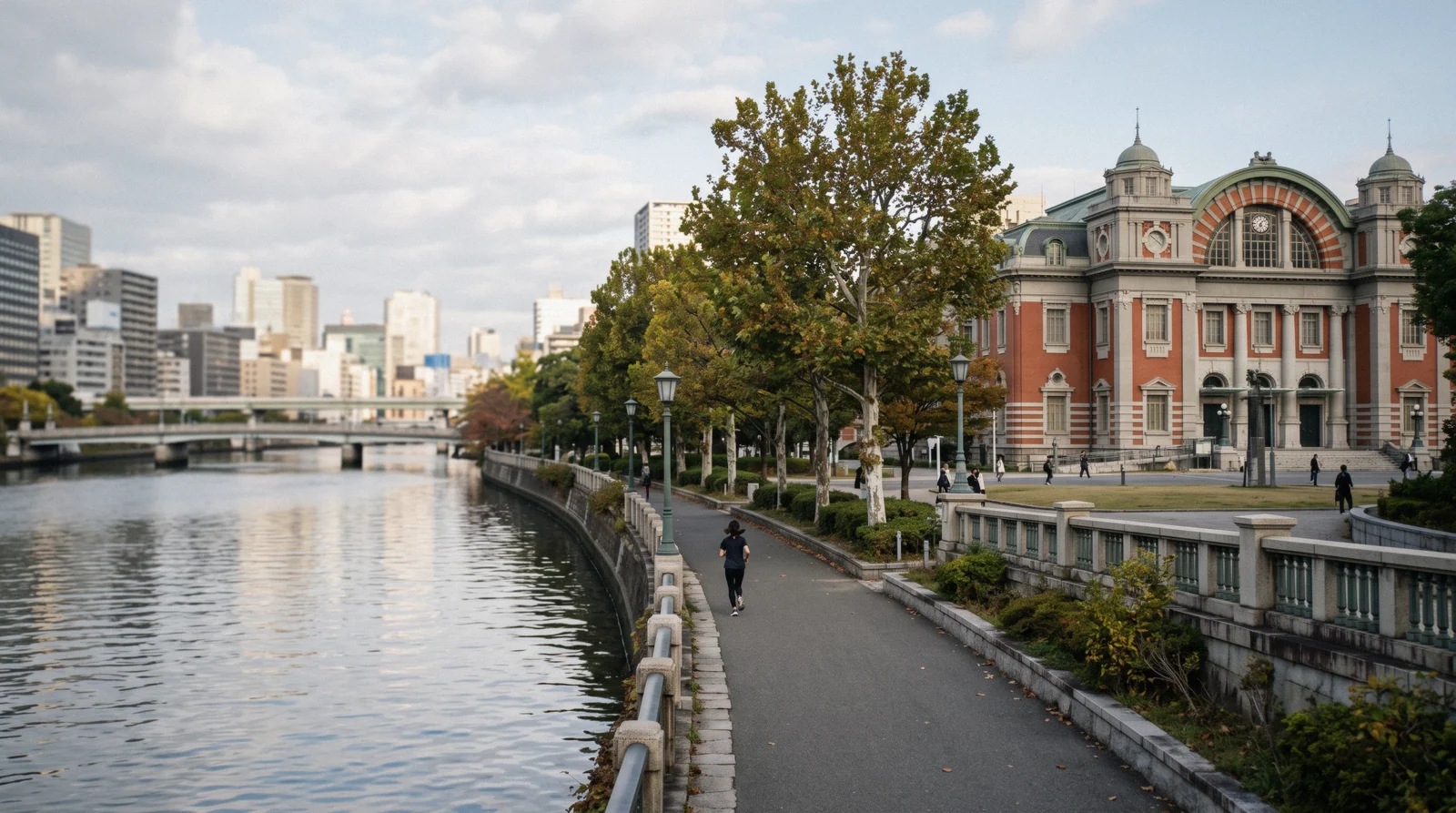The red-brick Central Public Hall on the riverbank at 08:30 with the water and the office towers behind it, Nakanoshima Osaka Japan